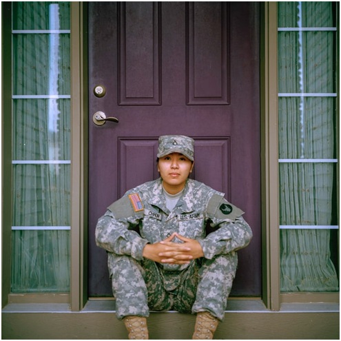 military service member sitting in front of their house